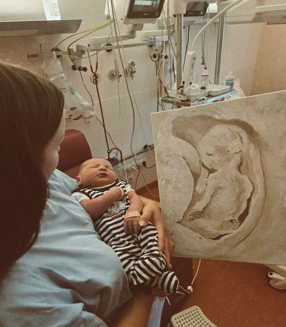 Frau im Krankenhaus wurde bei der Geburt Überrascht mit einem Bild . Das Bild zeigt ein gemaltes Baby im Mutterleib